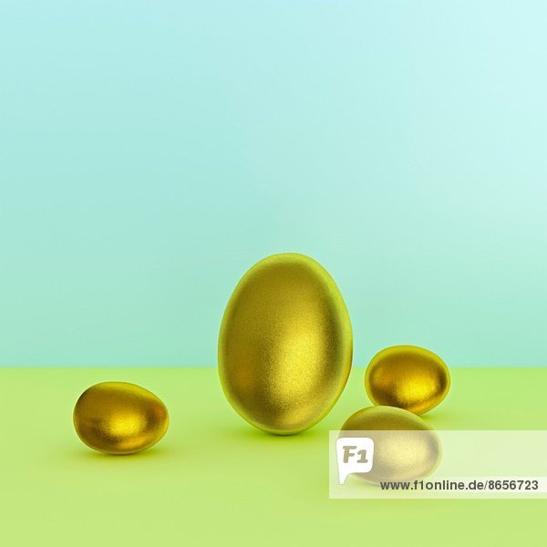 Stilleben von einem großen und drei kleinen goldenen Eiern