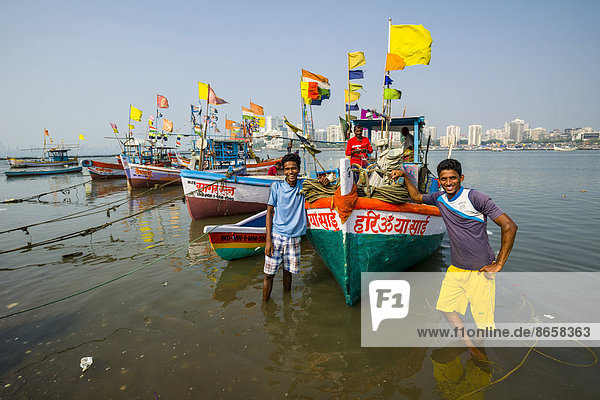 Fischer mit einigen Fischerbooten stehen vor der Skyline der Vorstadt Churchgate in der Back Bay  Mumbai  Maharashtra  Indien