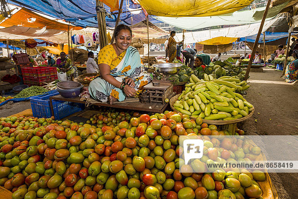 Eine Frau verkauft Tomaten und Gurken auf dem wöchentlichen Gemüsemarkt  Nasik  Maharashtra  Indien