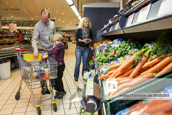 Family shopping with a shopping trolley in the fruit and vegetables department of a supermarket  Germany