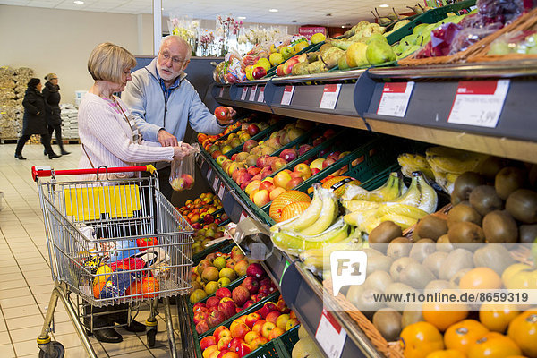 Senior couple shopping with a shopping trolley in the fruit and vegetables department of a supermarket  Germany