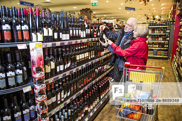 Senior couple shopping in the wine department in a supermarket  Germany
