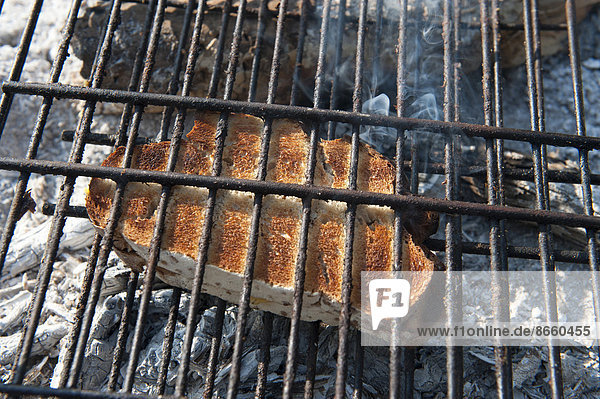 Slice of bread being toasted on a campfire  Kunene River Lodge  Kunene Region  Namibia