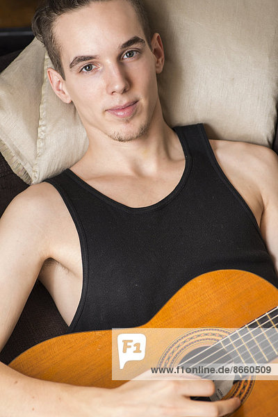 Young man relaxing and playing his acoustic guitar