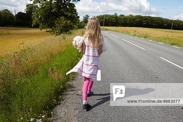 Girl carrying dog on country road  Skane  Sweden