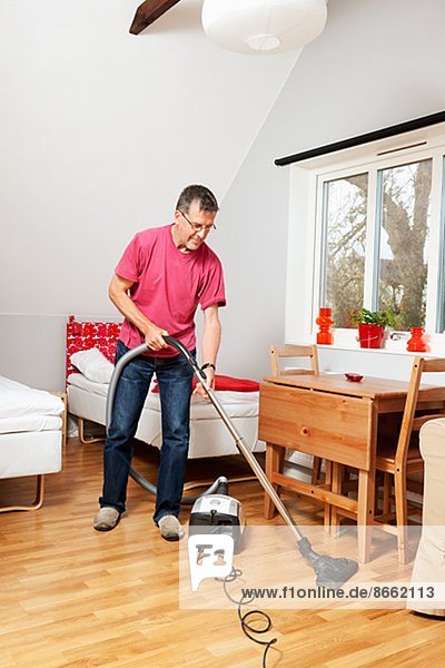 Mature man vacuum cleaning room  Gotland  Sweden