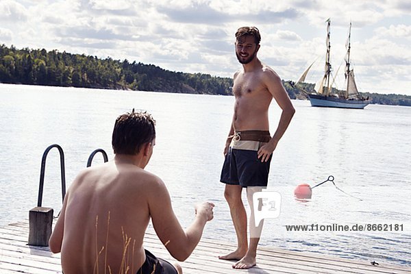 Two young men talking on jetty  Sweden