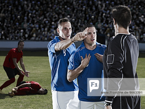 Fußballspieler streiten sich mit Schiedsrichter auf dem Spielfeld