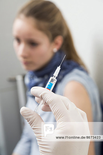 Arztpraxis  junge Frau bekommt eine Grippeschutzimpfung  Vaxigrip  Deutschland