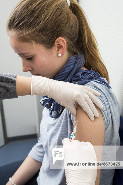 Arztpraxis  junge Frau bekommt eine Grippeschutzimpfung  Vaxigrip  Deutschland