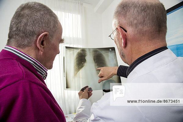 Doctor's office  doctor talking to an elderly patient about the x-ray image of a lung  Germany