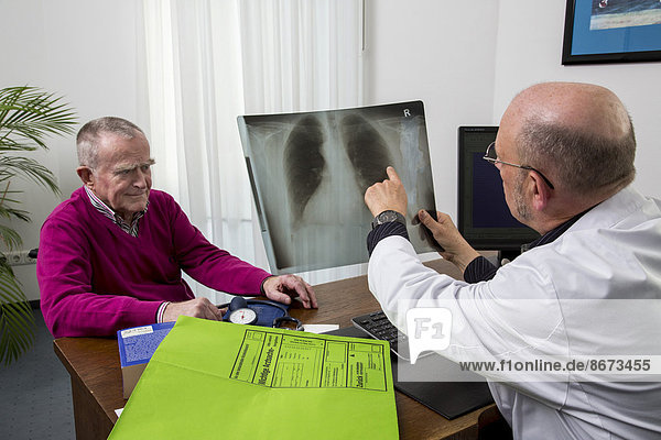 Arztpraxis  älterer Patient im Gespräch mit seinem Hausarzt  Besprechung einer Röntgenuntersuchung der Lunge  Deutschland
