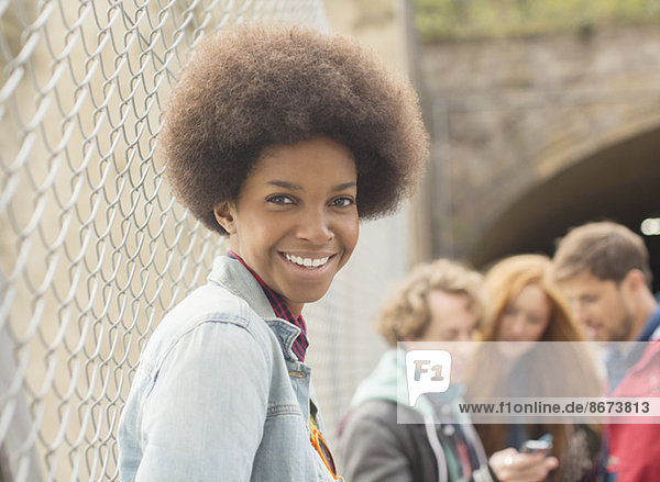 Woman smiling by chain link fence with friends in background
