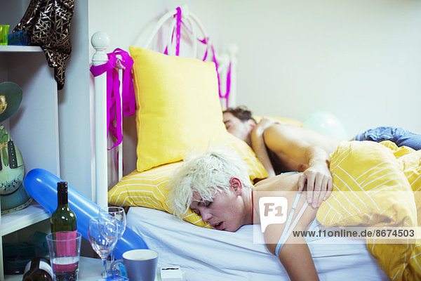 Couple sleeping in bed the morning after a party