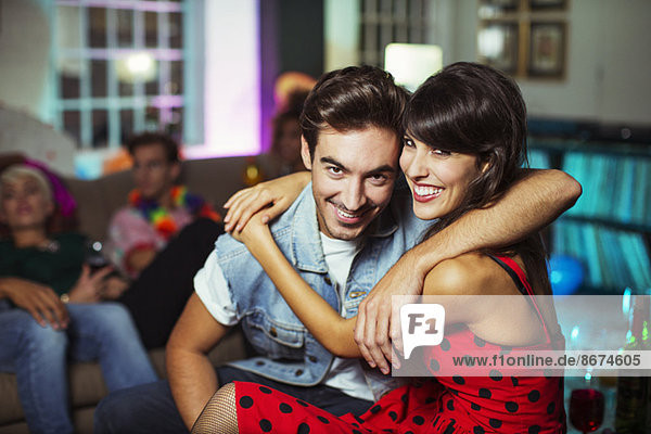 Couple hugging in living room at party