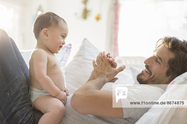 Father playing with baby son on sofa