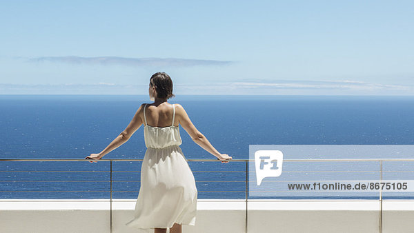 Frau schaut vom Balkon auf den Ozean