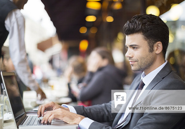 Businessman using laptop at sidewalk cafe