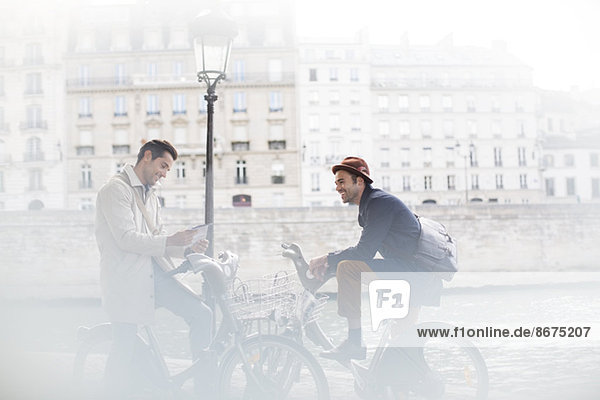 Businessmen talking on bicycles along Seine River  Paris  France