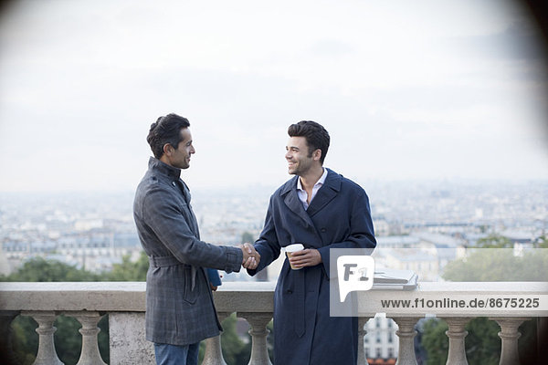 Geschäftsleute beim Händeschütteln am Geländer mit Blick auf Paris  Frankreich