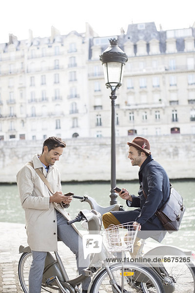 Businessmen with cell phones on bicycles along Seine River  Paris  France