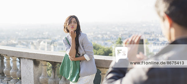 Mann fotografiert Freundin mit Paris im Hintergrund