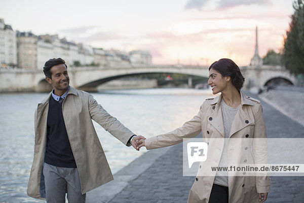 Couple holding hands along Seine River  Paris  France