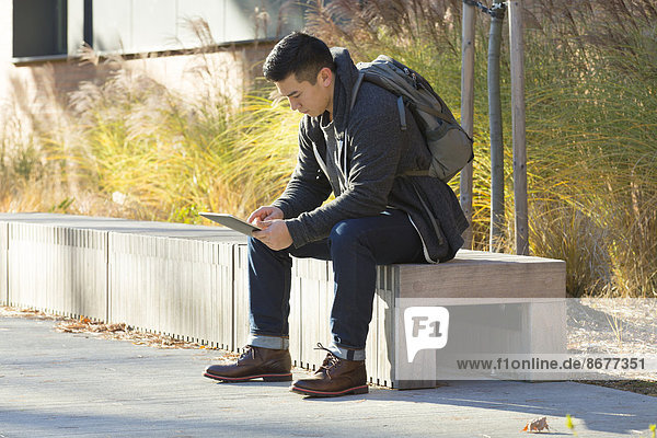 Mixed race college student using digital tablet on campus