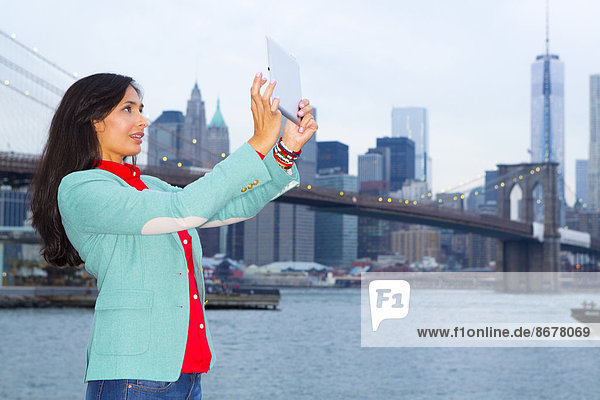 Mixed race woman taking pictures at waterfront  New York  New York  United States