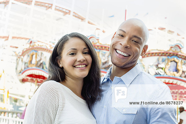 Mixed race couple smiling at amusement park