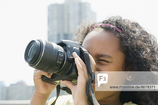 Mixed race girl taking pictures outdoors