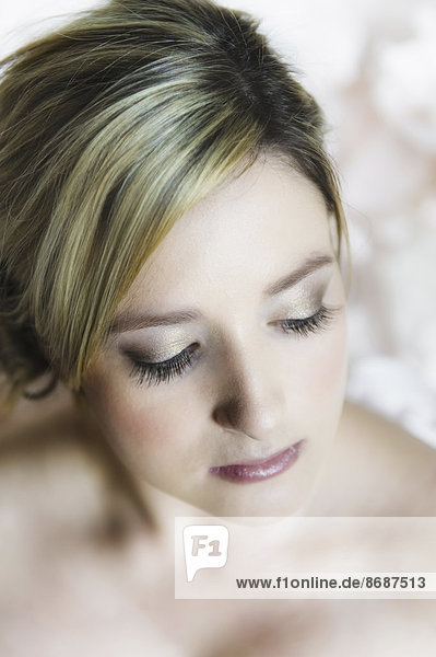 Das Porträt einer jungen Frau mit blonden Haaren vor einem weißen Hintergrund. Nahaufnahme ihres Gesichts.