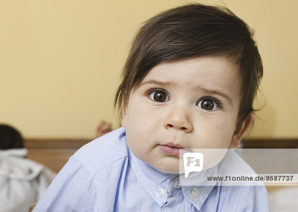Ein kleines Kind mit runden Augen und schwarzen Haaren  das in die Kamera schaut.
