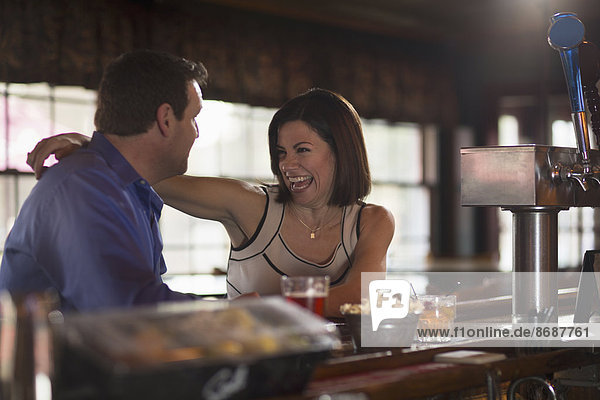 Ein Mann und eine Frau sitzen an einer Bar  flirten und unterhalten sich. Bei einem Date.