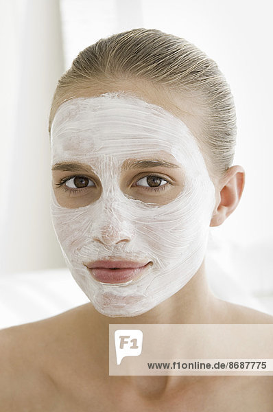 Ein Spa-Behandlungszentrum. Eine junge Frau mit einer weißen Gesichtsmaske auf der Haut.