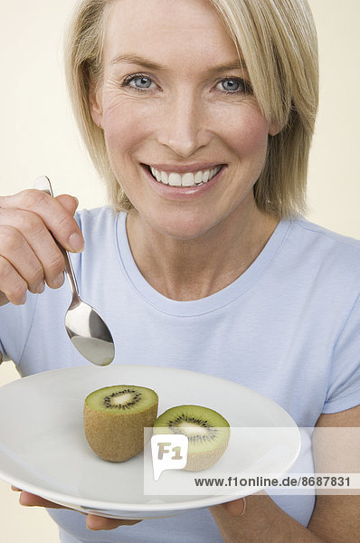 Eine Frau isst eine Kiwifrucht.