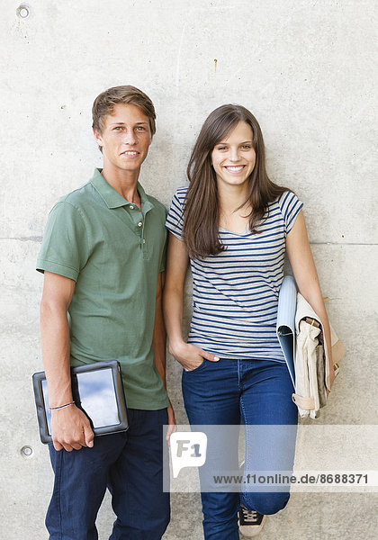 Junges Paar steht vor Betonmauer