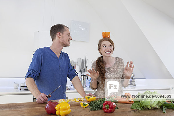 Junge Frau balanciert orangefarbene Paprika auf dem Kopf