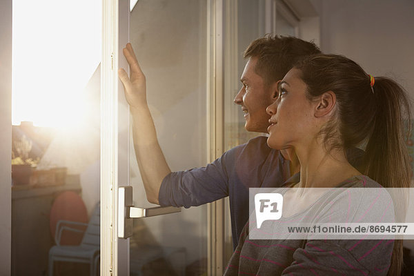 Couple standing at open window
