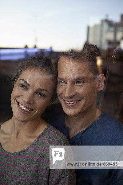Portrait of smiling couple behind window