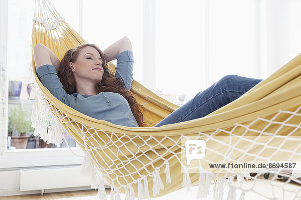 Frau entspannt sich in einer Hängematte in ihrer Wohnung