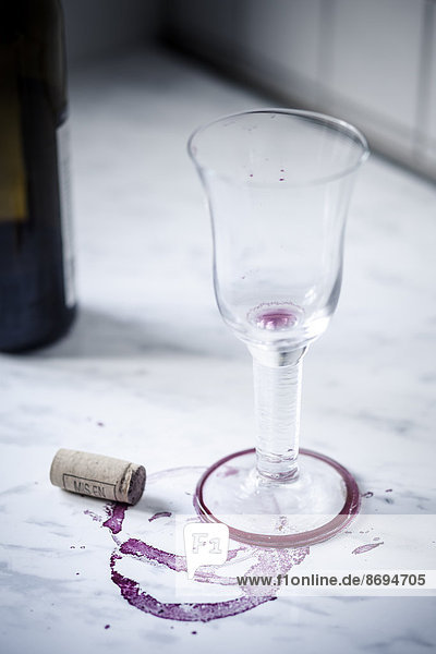 Leeres Rotweinglas  Flasche  Flecken und Weinkorken auf weißem Marmor