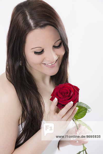 Junge Frau lächelt rote Rose an