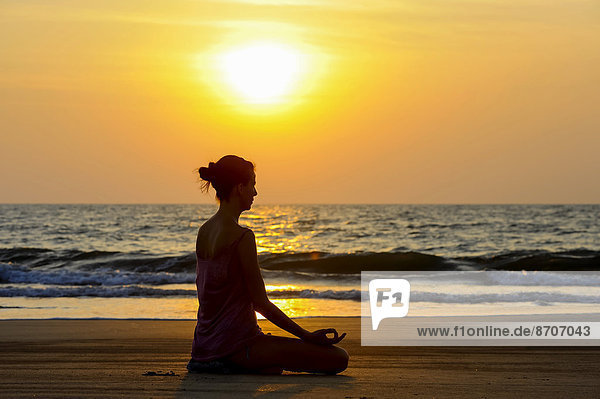 Frau meditiert bei Sonnenuntergang am Strand  Kerala  Indien