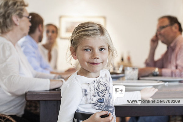 Portrait of girl sitting with family at dining table