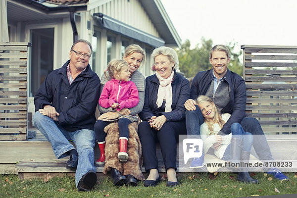 Porträt einer glücklichen Mehrgenerationen-Familie,  die zusammen im Hof sitzt
