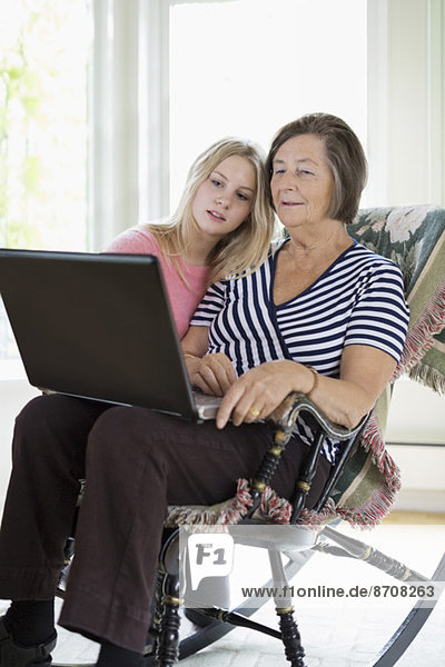 Grandmother and granddaughter using laptop at home