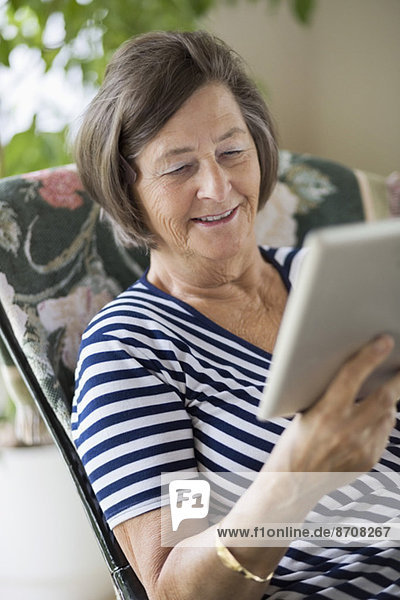 Lächelnde Seniorin mit digitalem Tablett zu Hause