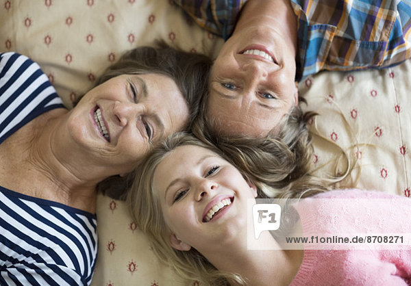 Overhead-Porträt von glücklichen Drei-Generationen-Weibchen auf dem Bett liegend