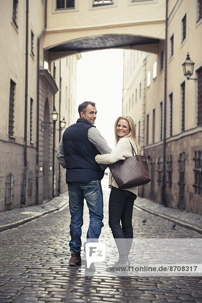 Full length of happy couple walking on city street